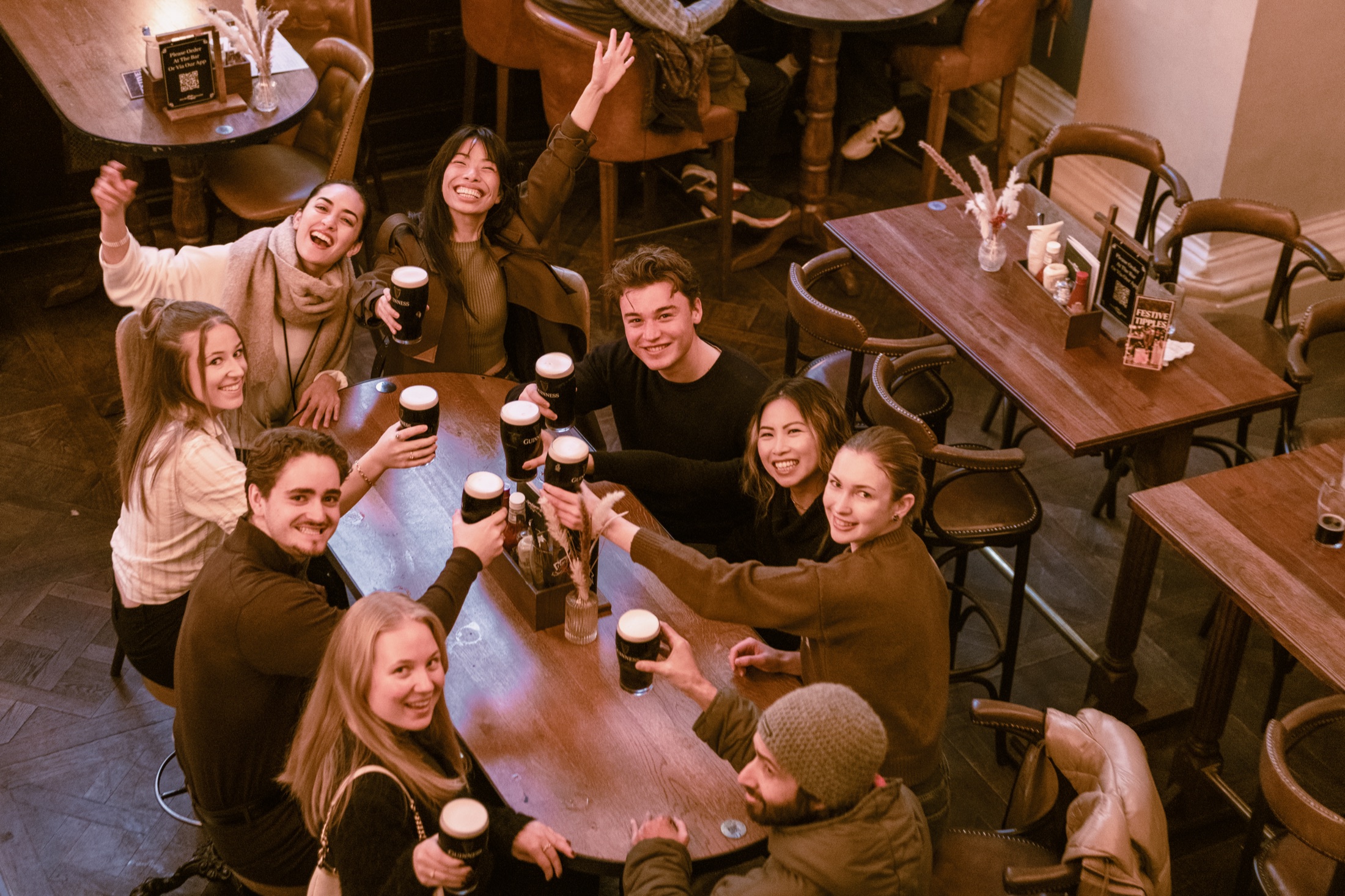 Friends gathered around a pub table raising their pints